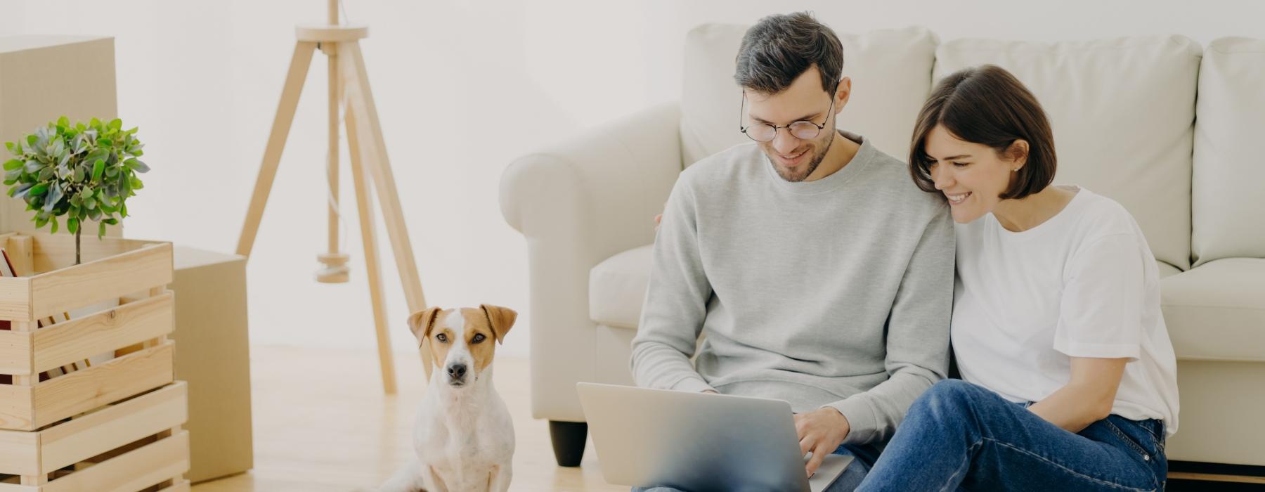 a man and a woman sitting on the floor with a dog